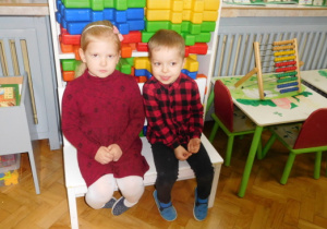 dwoje dzieci siedzących na ławeczce w grupie