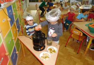 dzieci wyciskają sokz użyciem sokowirówki