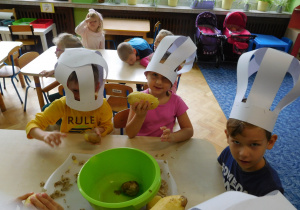 dzieci w czapkach kucharskich podczas przygotowania sałatki z warzyw