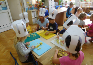 dzieci w czapkach kucharskich podczas przygotowania sałatki z warzyw