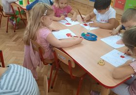dzieci malują farbami na kartkach przy stoliku