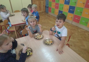 dzieci samodzielnie wykonują sałatkę owocową siedząc przy stoliku