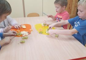dzieci samodzielnie wykonują sałatkę owocową siedząc przy stoliku