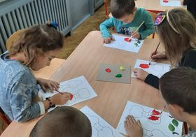 dzieci malują farbami na kartkach przy stoliku
