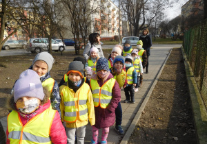 grupa dzieci w odblaskowych kamizelkach na chodniku