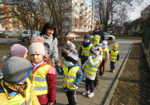 grupa dzieci w odblaskowych kamizelkach na chodniku