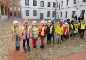 grupa dzieci w odblaskowych kamizelkach na terenie Muzeum