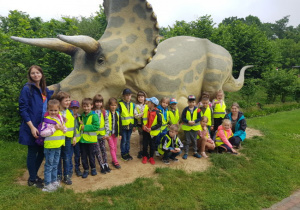 dzieci w parku przy pomniku dinozaura