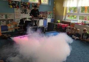 dzieci w sali podczas zabawy z DJ ze sztucznym dymem