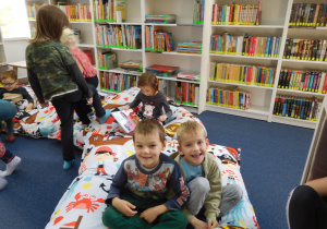 dzieci w sali bibliotecznej na miękkich poduchach