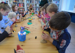 dzieci podczas działań plastycznych przy stołach