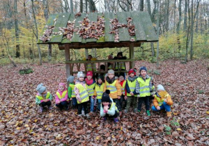 grupa dzieci w odblaskowych kamizelkach w lesie