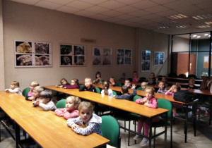 grupa dzieci siedząca w łakach szkolnych w muzeum