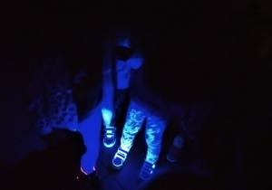 podświetlone nogi dzieci w specjalnej sali muzealnej wykorzystującej światło fluorescencyjne