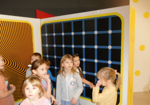 dzieci przy obrazie z wieloma punktami wywołującymi różne zjaiska optyczne