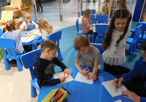 dzieci przy stolikach malujące farbami