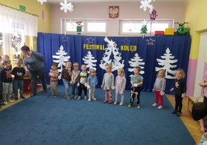 dzieci podczas występu na tle dekoracji ściennej z napisem festiwal kolęd