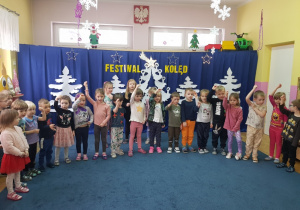 dzieci podczas występu na tle dekoracji ściennej z napisem festiwal kolęd