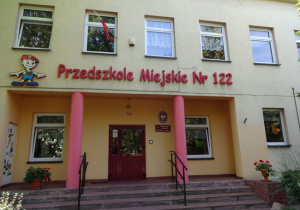 budynek Przedszkola widziany z zewnątrz z czerwonym napisem "Przedszkole Miejskie Nr 122"